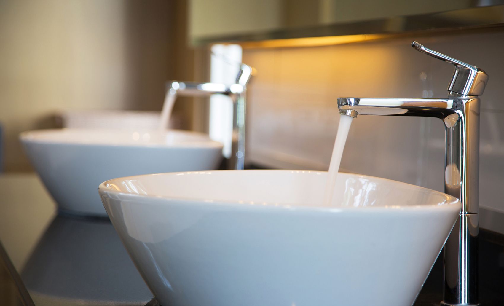 Zwei weiße Waschbecken auf einer Platte.